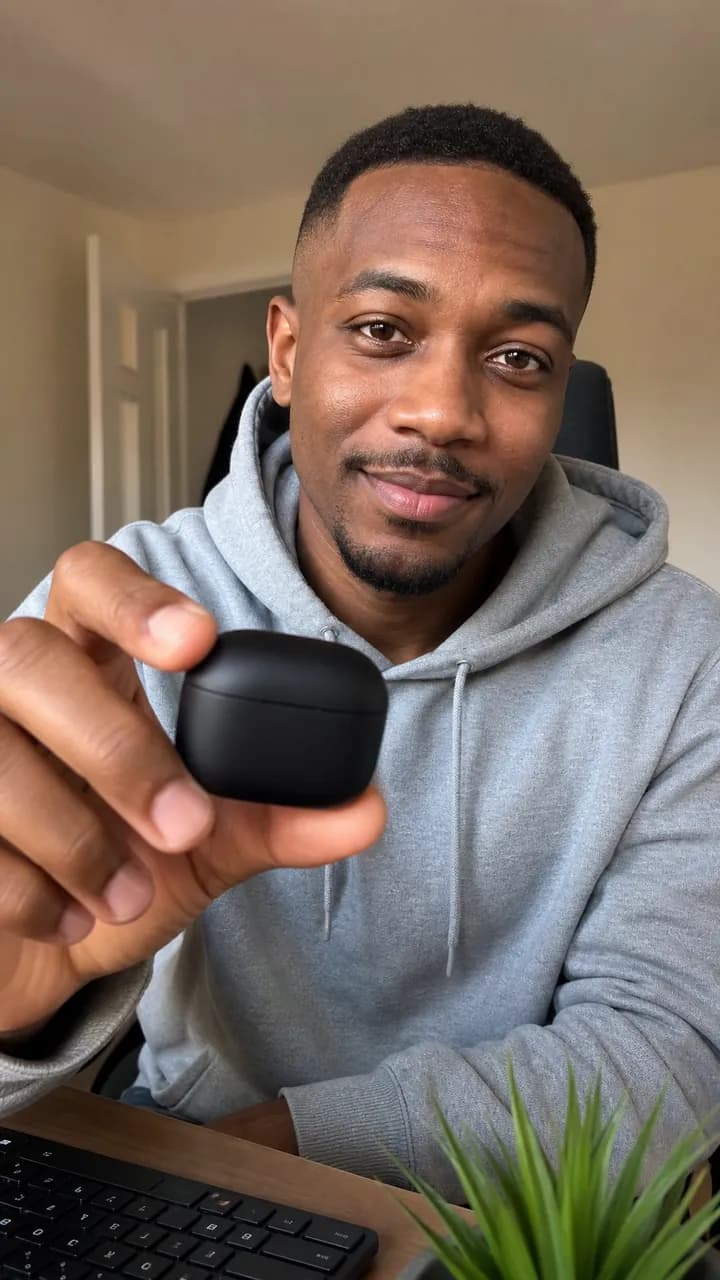 Marcus O. holding an earbud case at a desk with a small plant